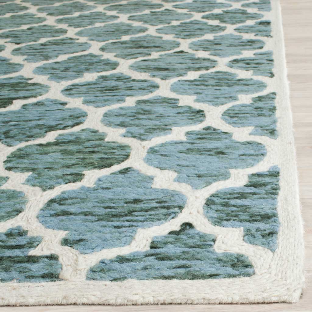 Ivory trim surrounds textured teal quatrefoils on this softly patterned wool rug