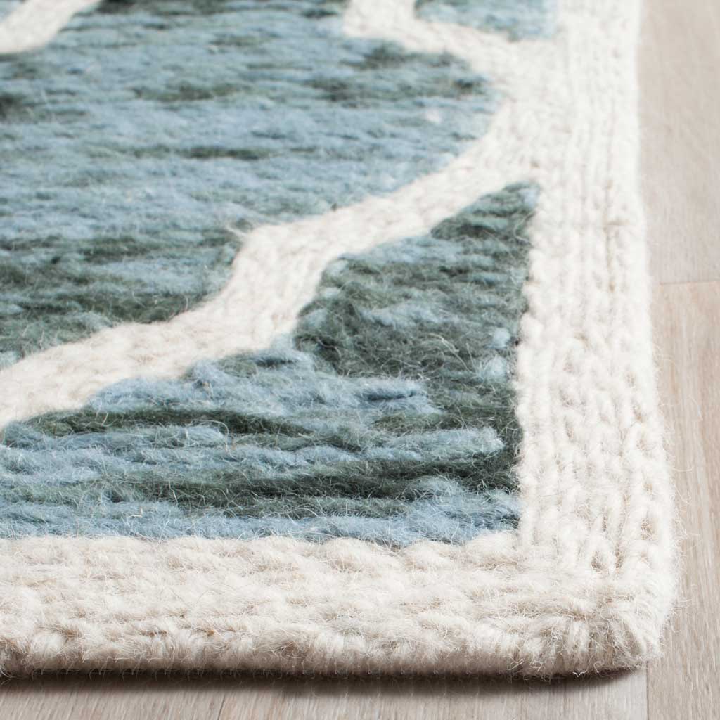 Plush ivory wool edging frames softly mottled turquoise motifs along the finished rug edge