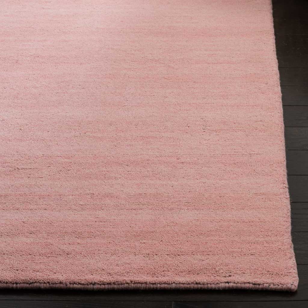 Pink wool-blend fibers and a neatly finished edge soften the rug's tonal surface