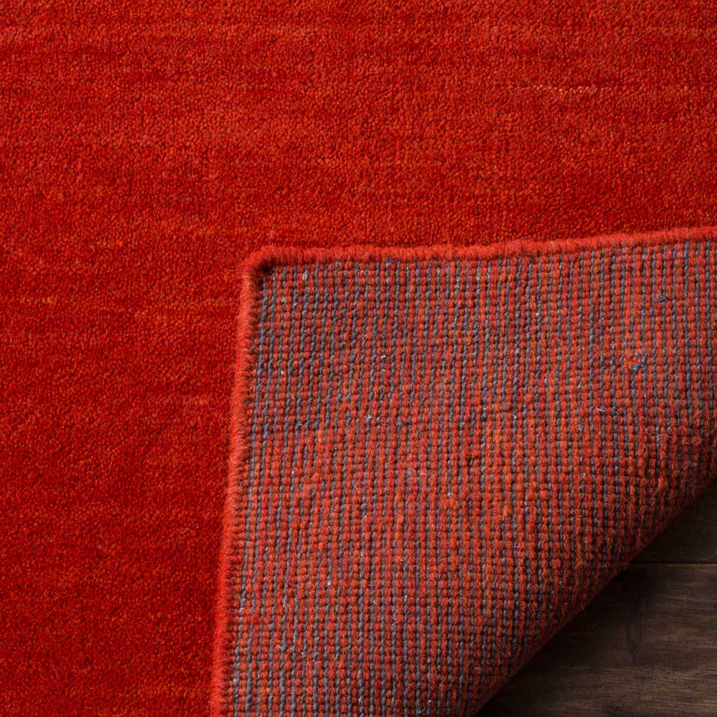 Turned-back corner reveals the red rug's woven underside and tidy edge finish