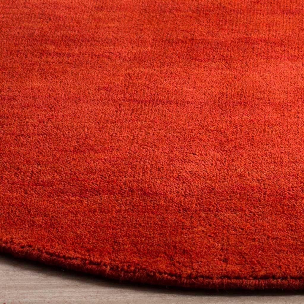Textured red wool-cotton pile and a neatly finished, low-profile rug edge