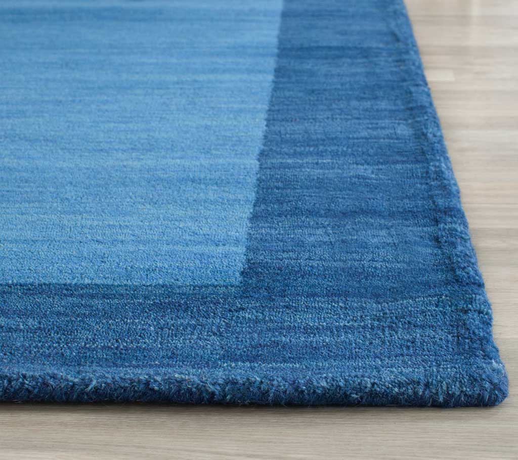Soft blue wool pile and a deep blue border meet at a neatly finished corner