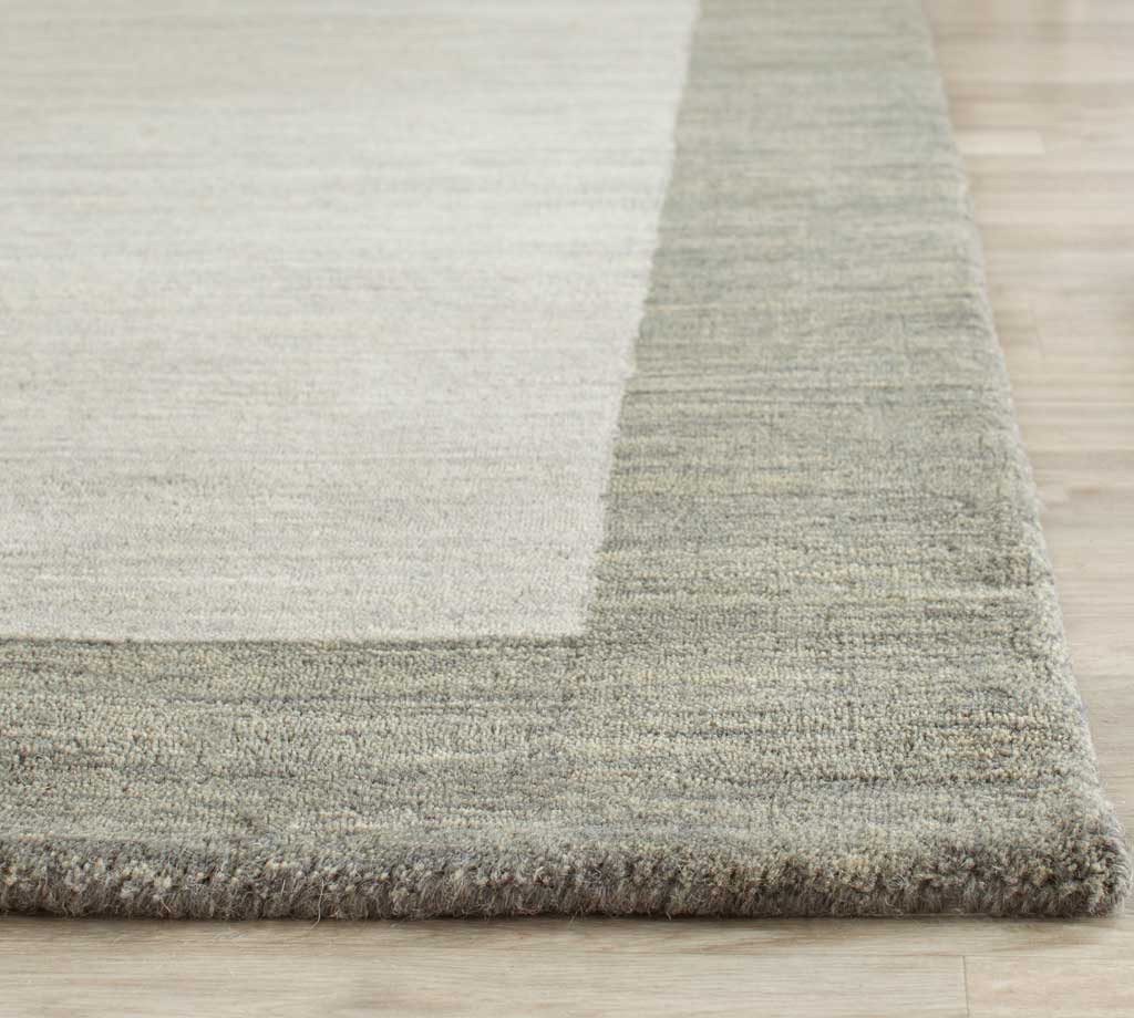 Soft wool texture and a darker gray border finish the rug's corner