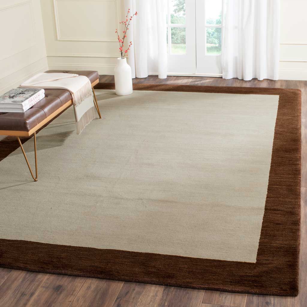 Beige wool rug with a dark brown border brings warmth to a bright living space