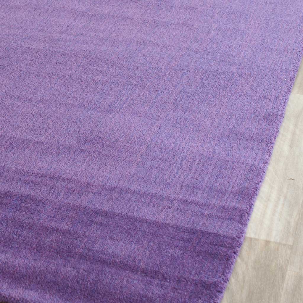 Plush lilac-purple fibers reveal gentle striations beside the rug's clean edge