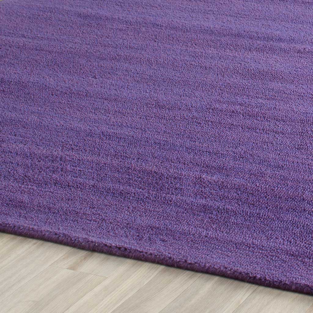 The square rug's purple pile has soft tonal ripples and a neatly finished edge