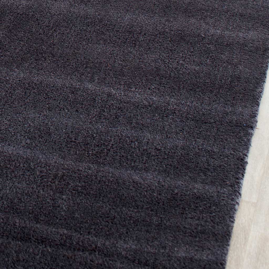 Velvety black pile displays subtle charcoal streaks beside a neatly finished edge