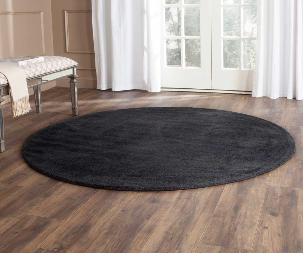 A round black rug anchors the room with an elegant dark tone and soft pile