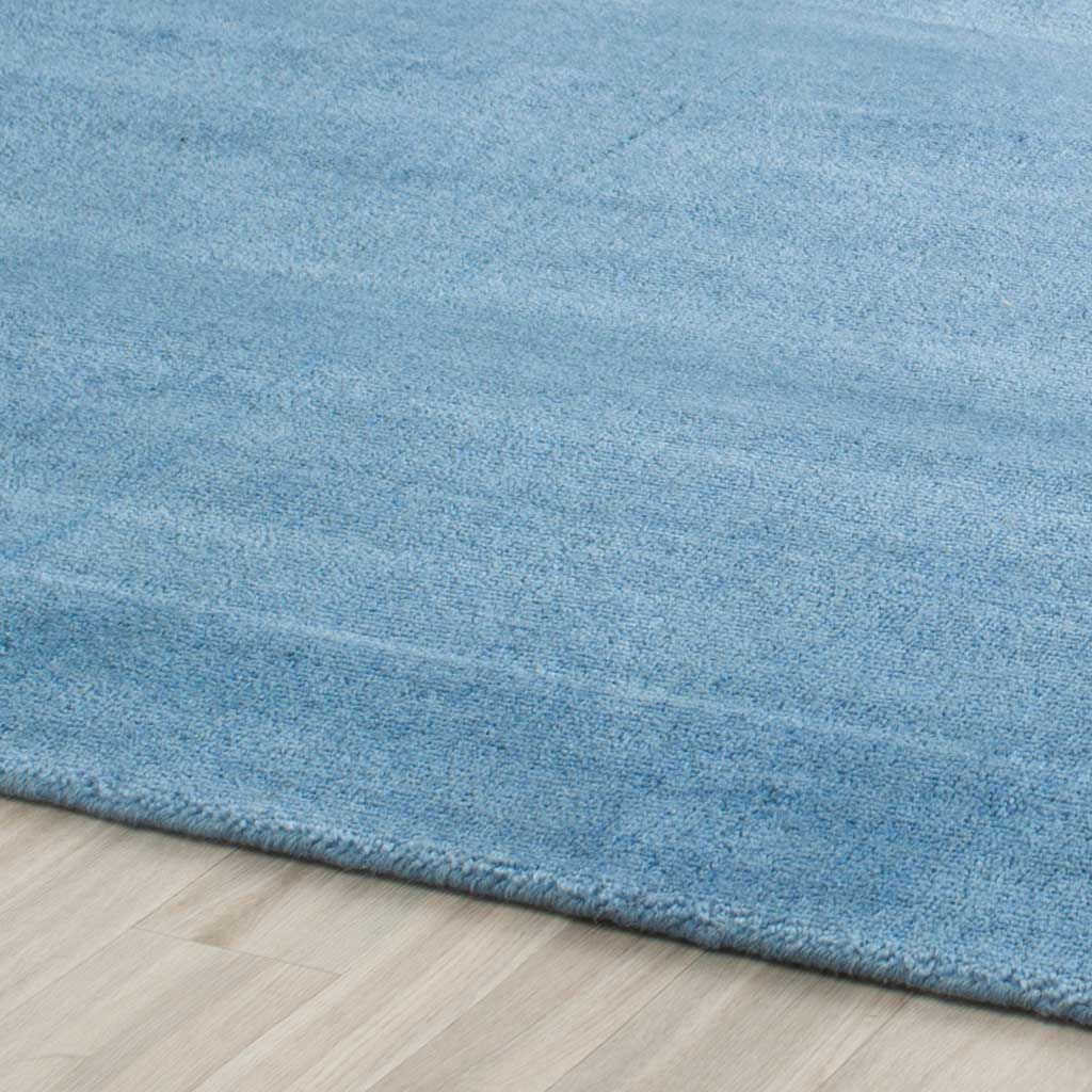 Soft blue fibers and fine tonal shifts lead to a clean, neatly bound rug edge