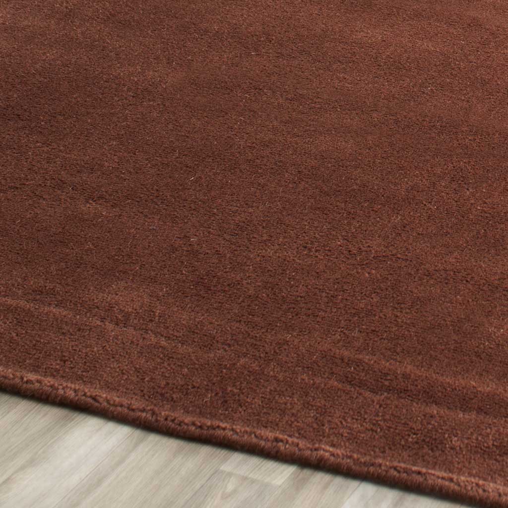 Warm brown fibers and subtle tonal streaks meet a tidy finished rug edge
