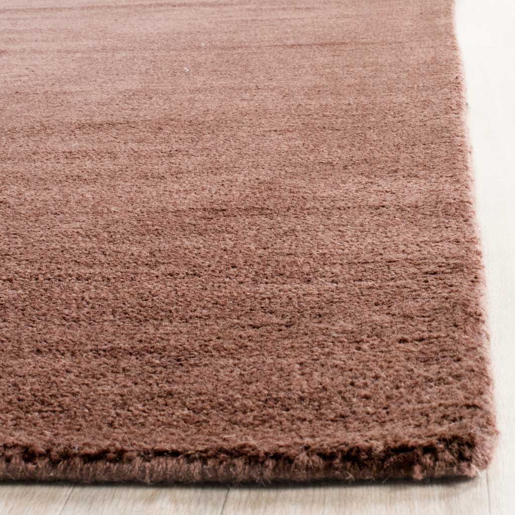 A thick, neatly finished corner highlights the brown rug's soft, dense pile