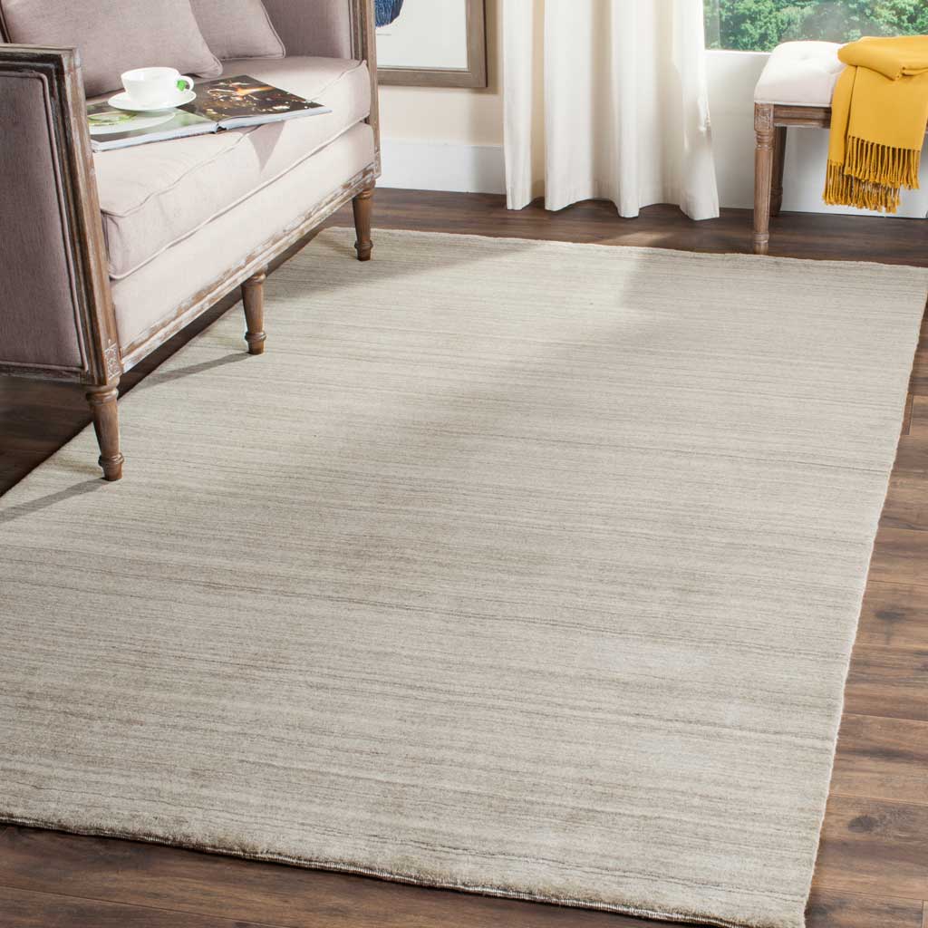 A stone-toned rug with delicate linear texture brings quiet softness beneath a sofa