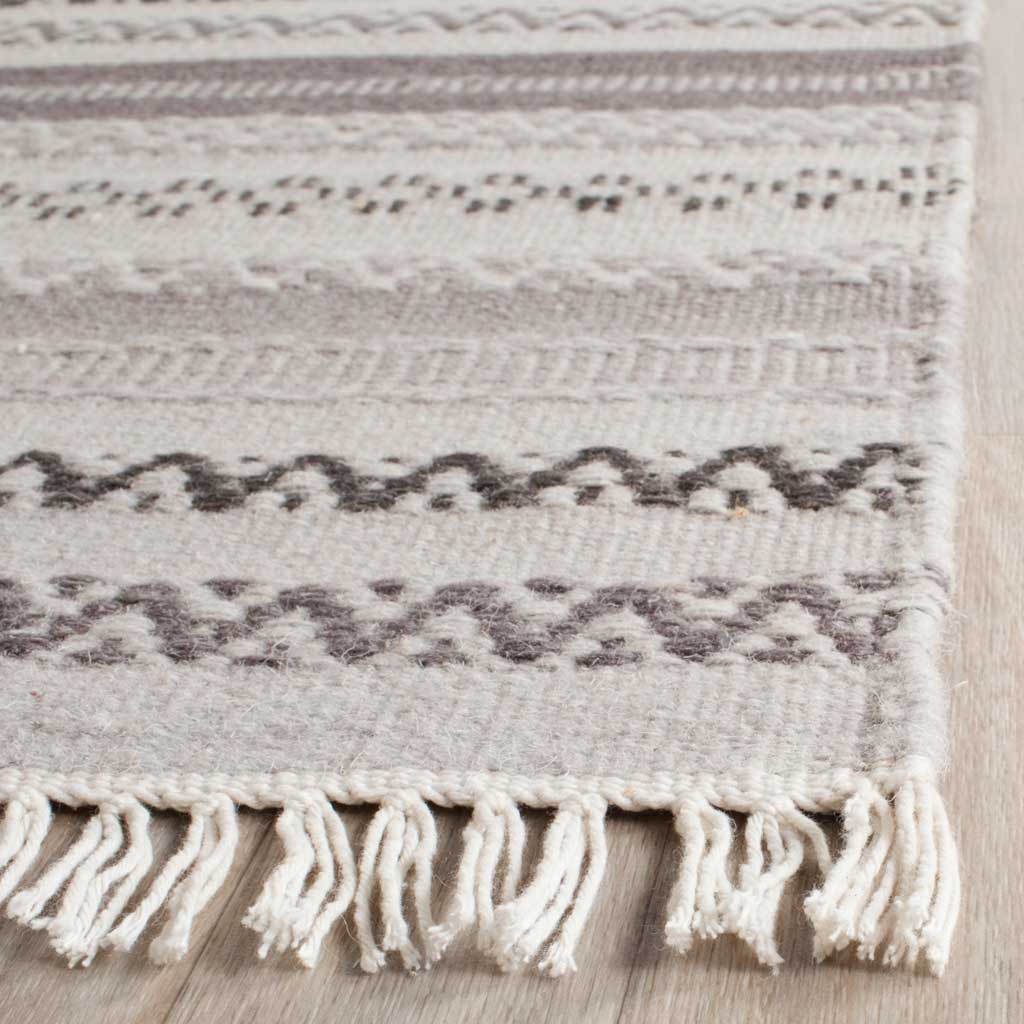 Textured gray and charcoal zigzags meet soft ivory fringe at this handwoven rug's edge