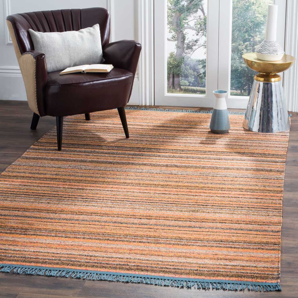 Soft pink, coral, and gray stripes bring warmth underfoot, framed by blue fringe