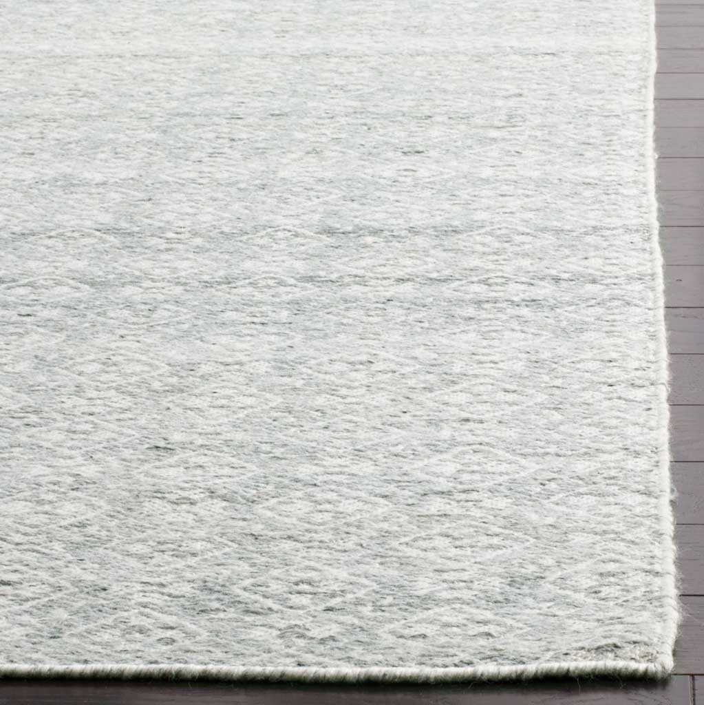 A textured wool weave and clean edge highlight the rug's pale silver-on-ivory pattern
