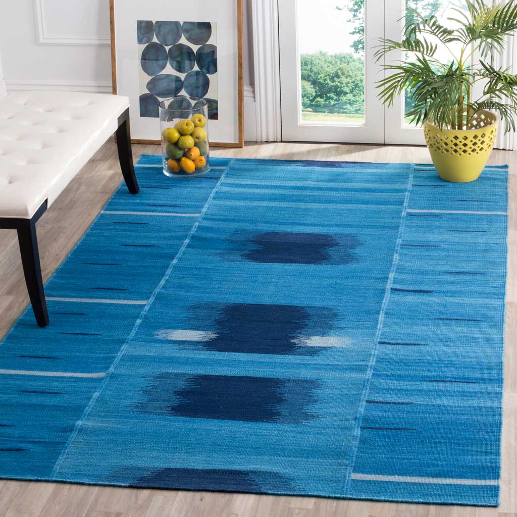Blue abstract rug anchors a bright living space with dark indigo motifs and fine ivory lines.