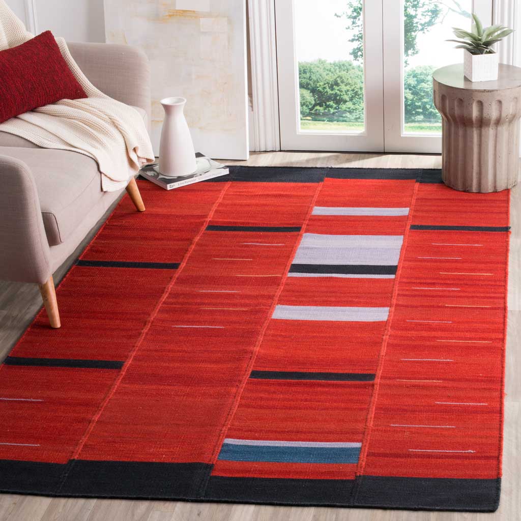 Bold red wool rug with black borders and blue-and-white stripes anchors a bright living area