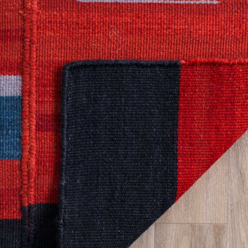 Dense woven underside reveals contrasting red and black sections of the wool rug