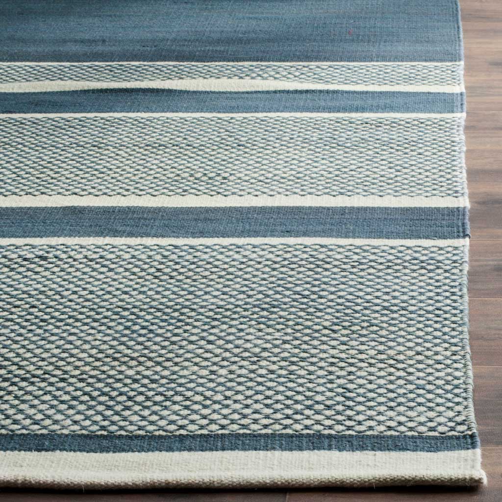 Intricate blue-on-ivory latticework meets wide blue stripes along a neatly finished rug edge.