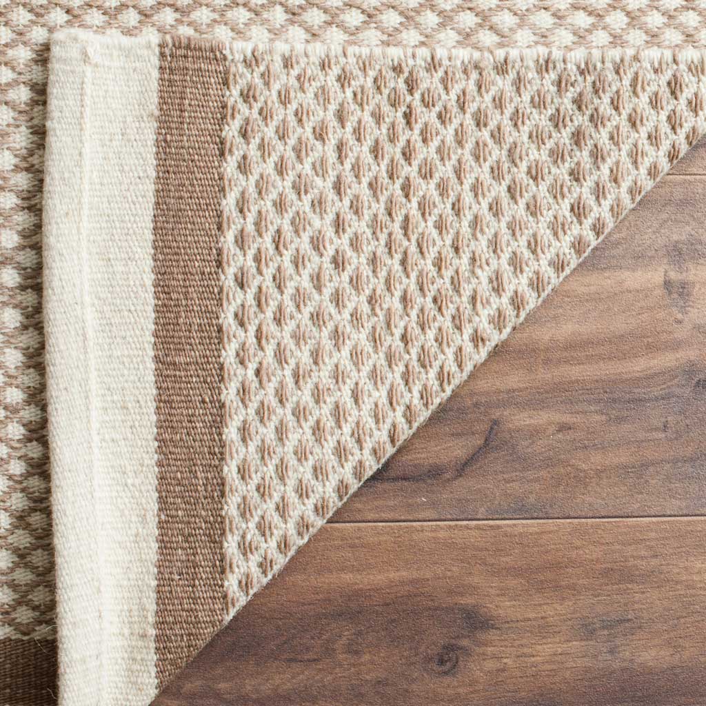 A folded edge exposes the brown and ivory rug's woven backing and finished border.