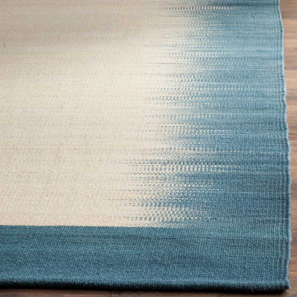 A neatly finished rug corner shows the textured weave and blue-to-beige color transition