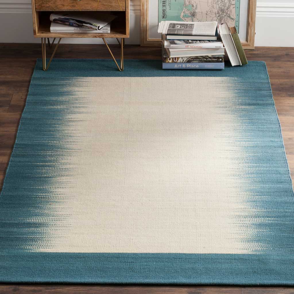 Blue ombre edges and a warm beige center bring soft contrast to wood flooring