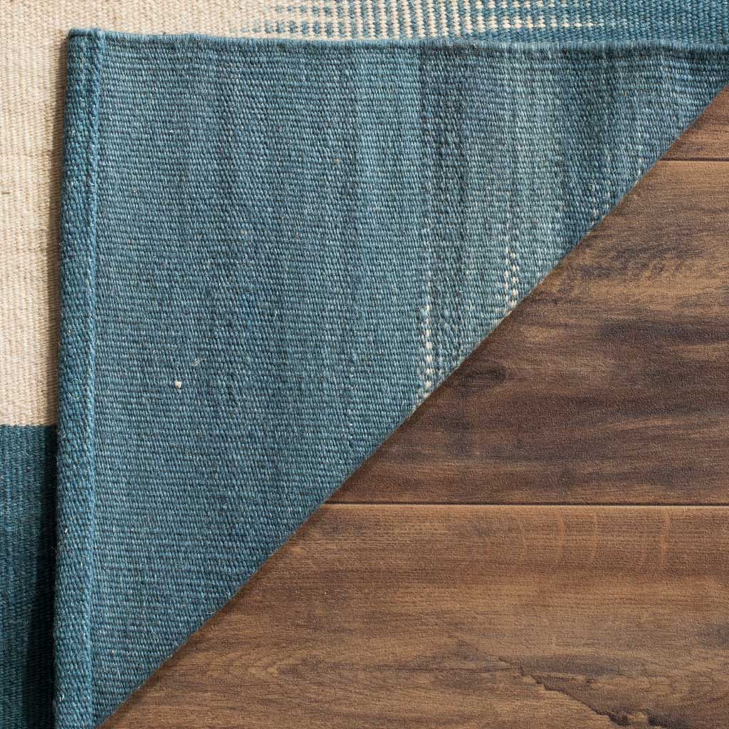 A folded rug corner reveals a tightly woven blue underside and tidy seams