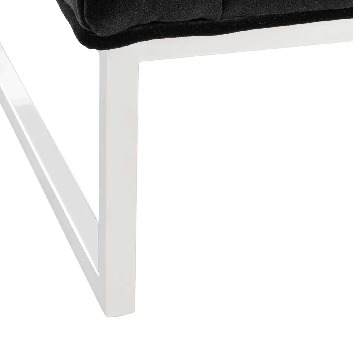 A polished chrome frame creates airy, angular support beneath the black velvet upholstery
