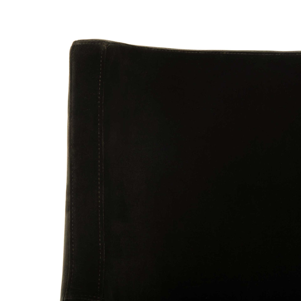 Subtle stitching defines the softly curved edge of the dark velvet backrest.
