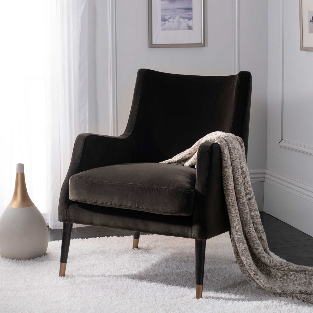 Rich shale velvet and slim brass-capped legs give this cushioned armchair cozy, vintage-inspired appeal.