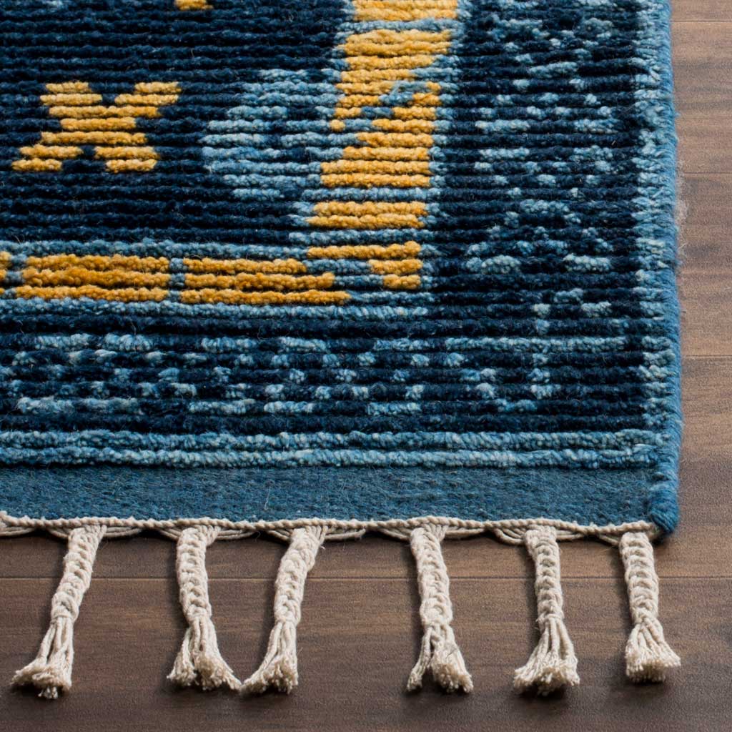 Gold accents and textured blue yarns meet a neatly bound edge and cream fringe