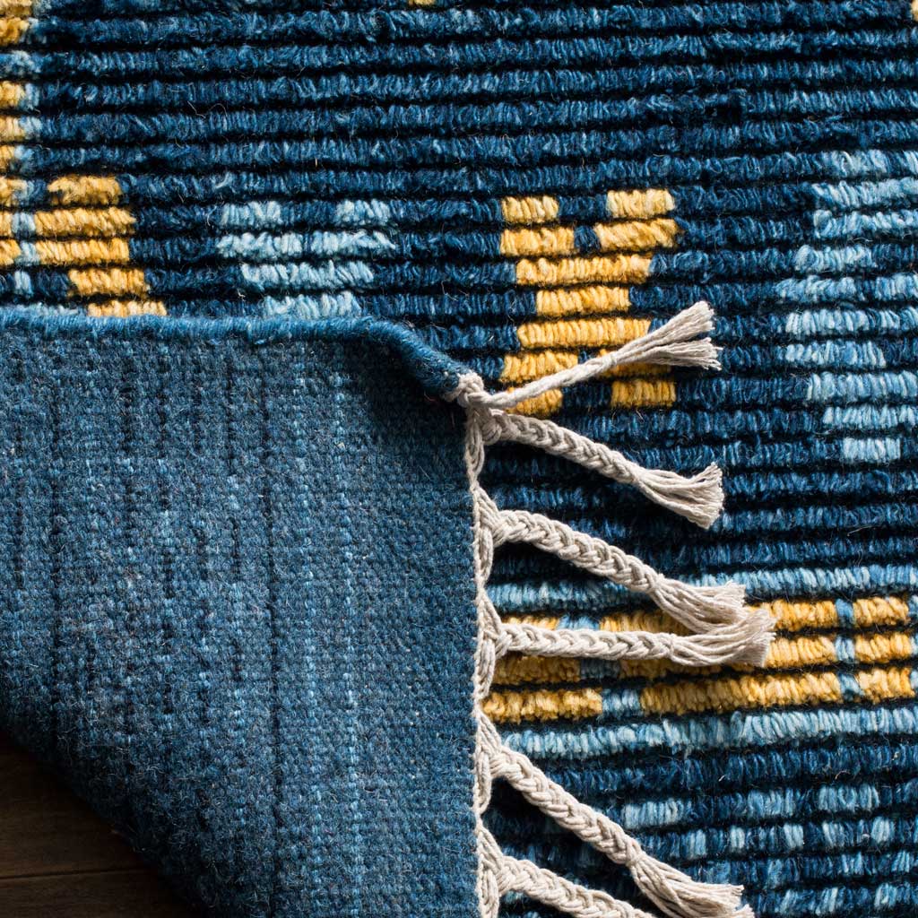 A folded edge reveals blue woven backing beneath the patterned pile