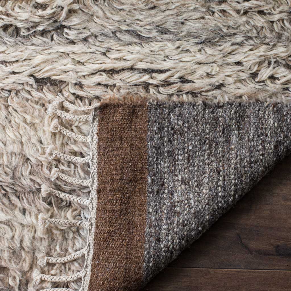 A folded edge reveals tightly woven gray backing beneath the rug's shaggy pile.