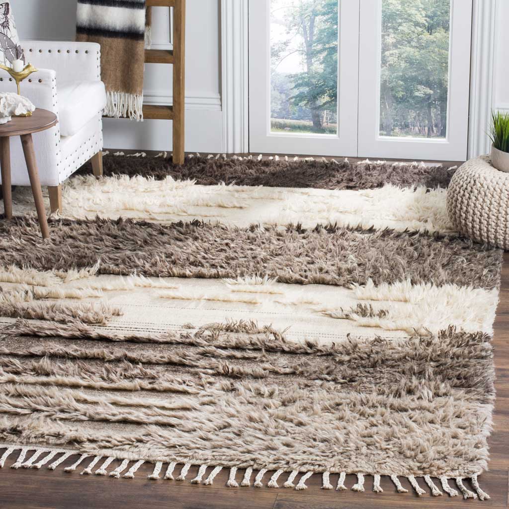 Broad charcoal, gray, and ivory stripes add plush texture and fringe to a bright living room