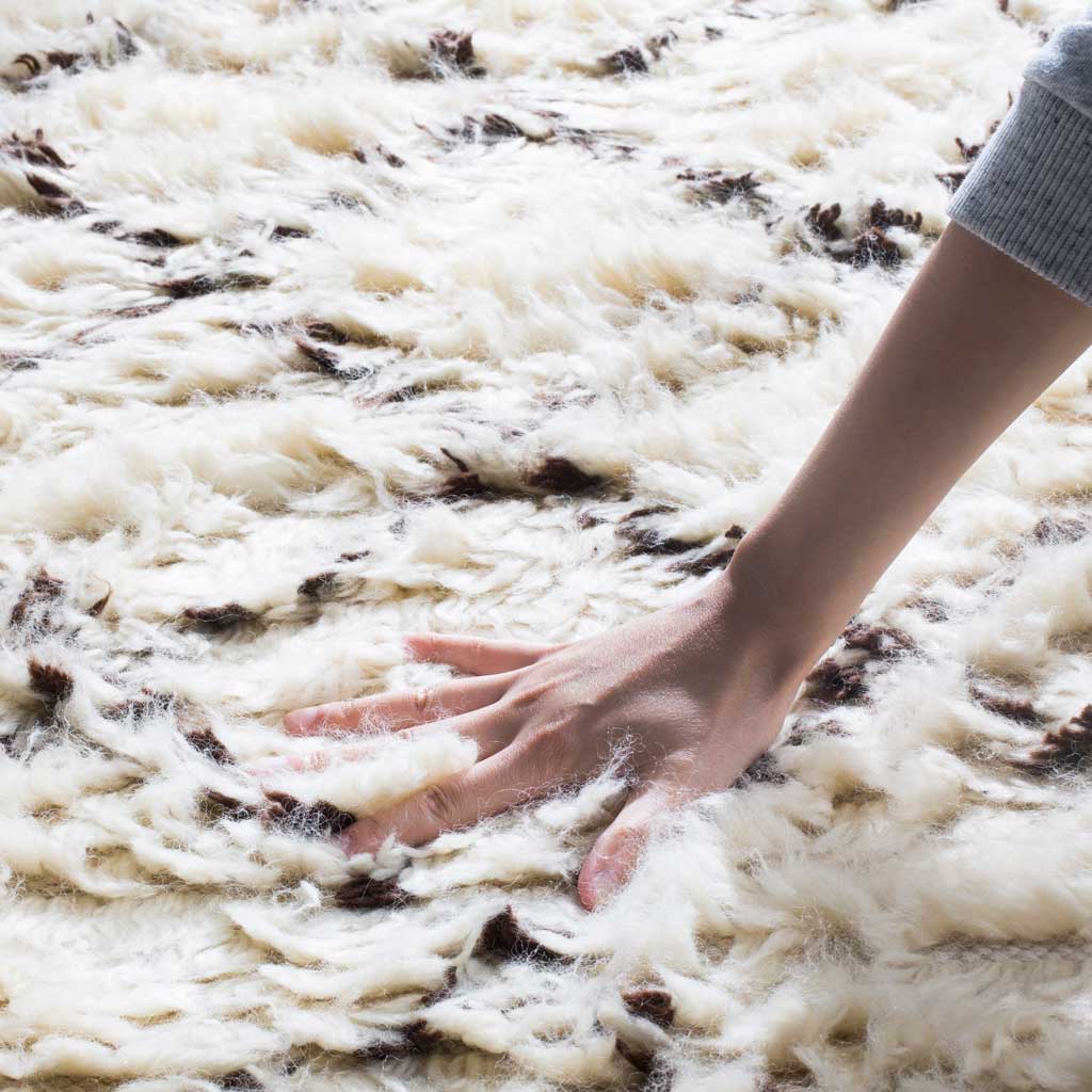 Fluffy ivory pile with dark brown accents offers a soft, touchable texture