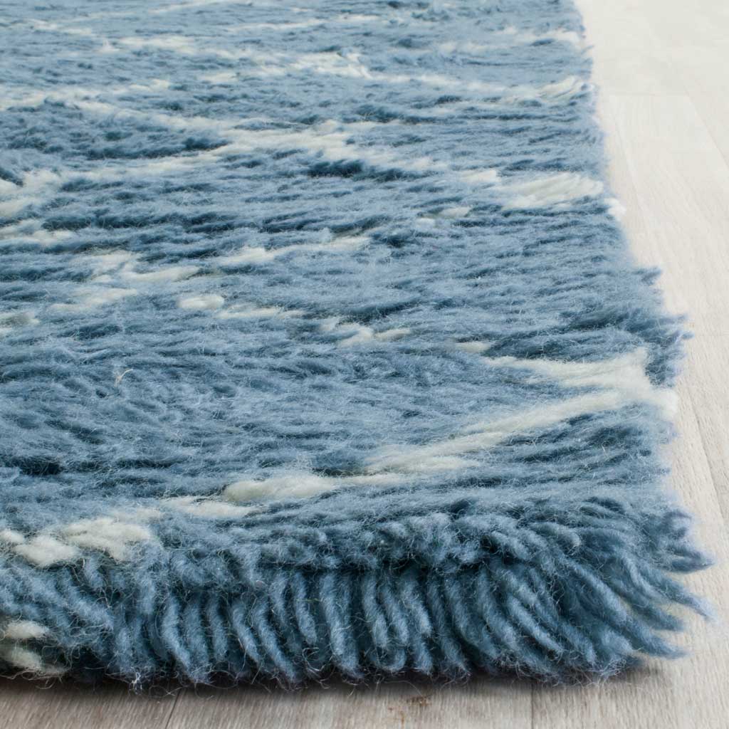 Dense blue fibers and ivory accents create a soft, shaggy rug edge