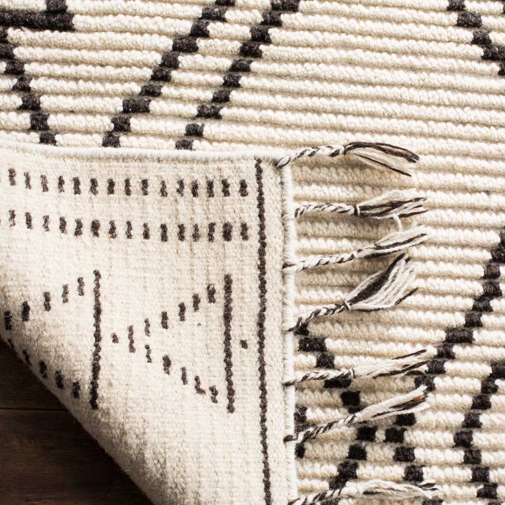 Ivory woven underside features black dotted motifs beside textured pile and twisted fringe