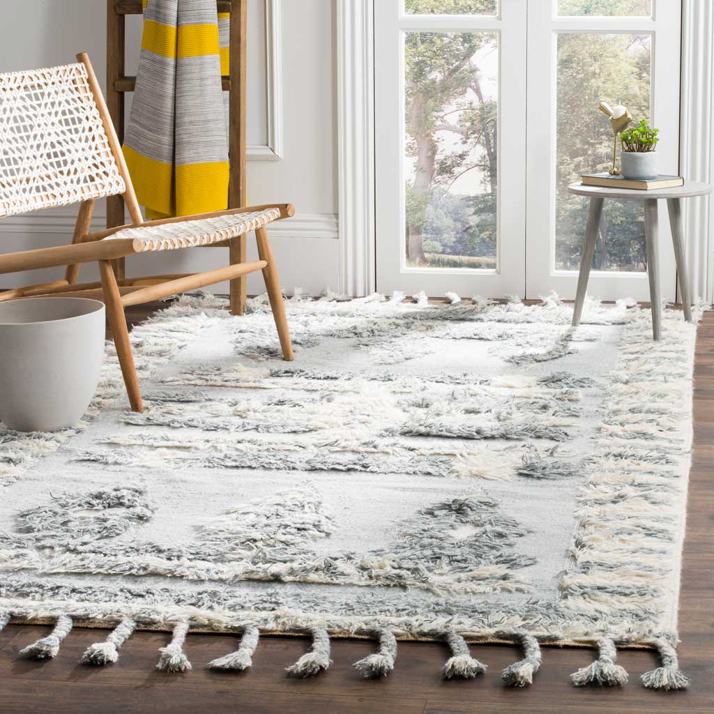 Gray and ivory rug with raised geometric motifs and fringe softens a light-filled seating area