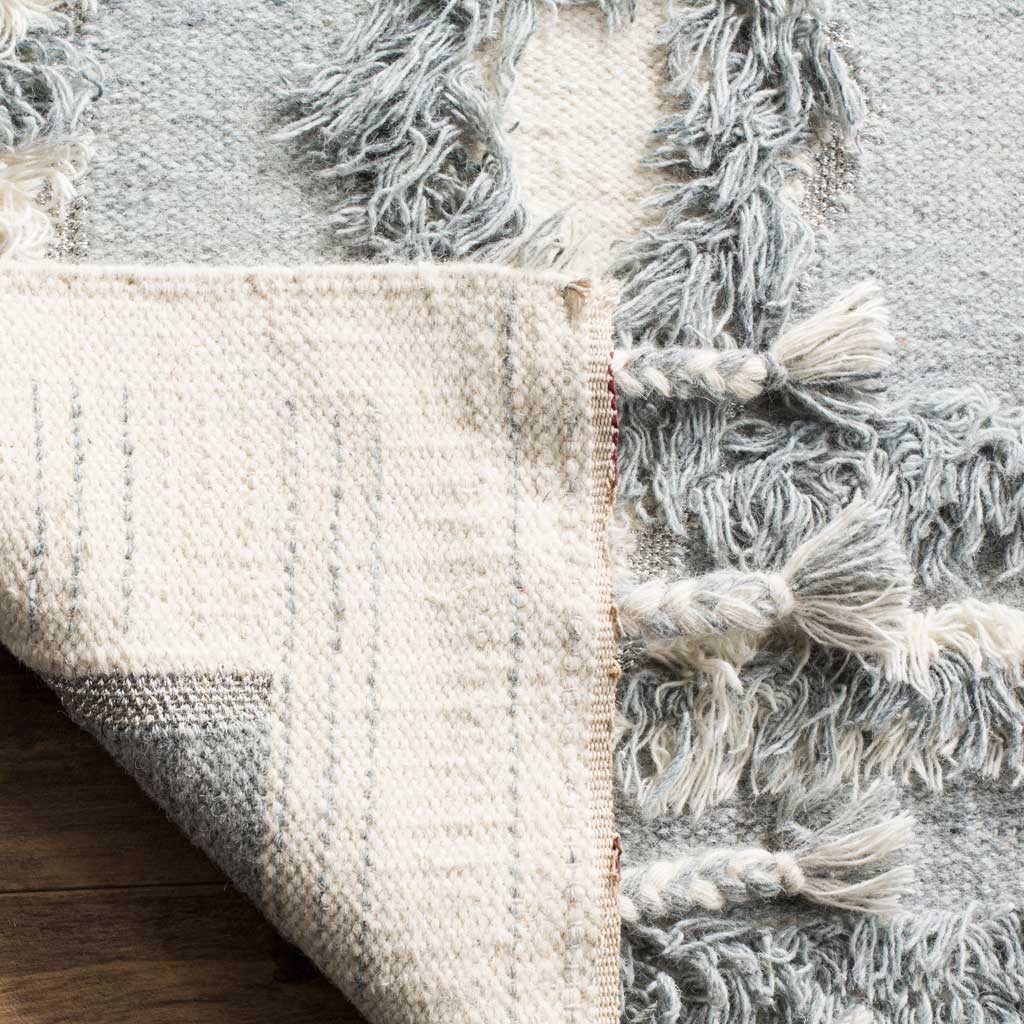 A folded corner exposes the ivory woven underside beneath the textured gray and ivory pile