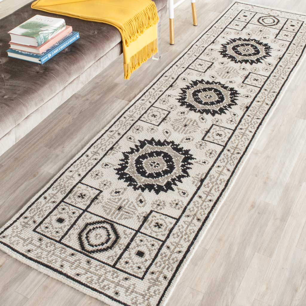 An ivory and gray runner brings bold medallions and intricate borders beside a sofa
