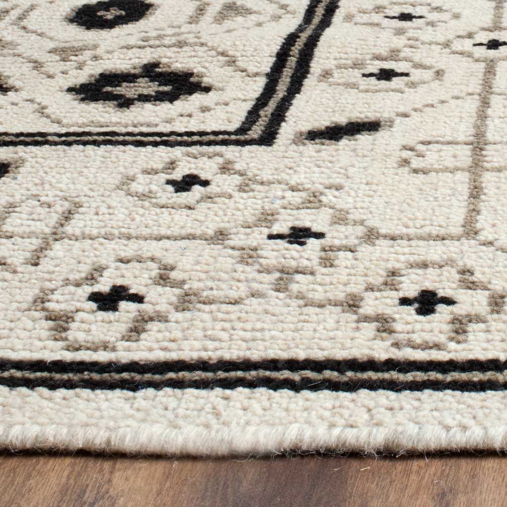 Textured ivory pile, small floral motifs, and crisp dark lines define the finished rug edge