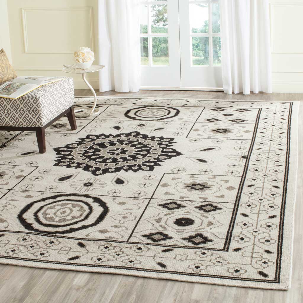 Ivory and gray rug pairs a bold floral centerpiece with intricate geometric panels and borders