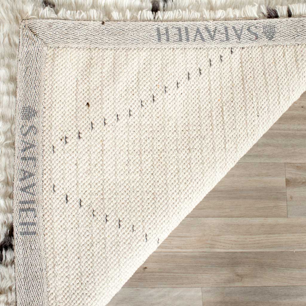 Woven backing with herringbone edging supports the rug's plush ivory pile