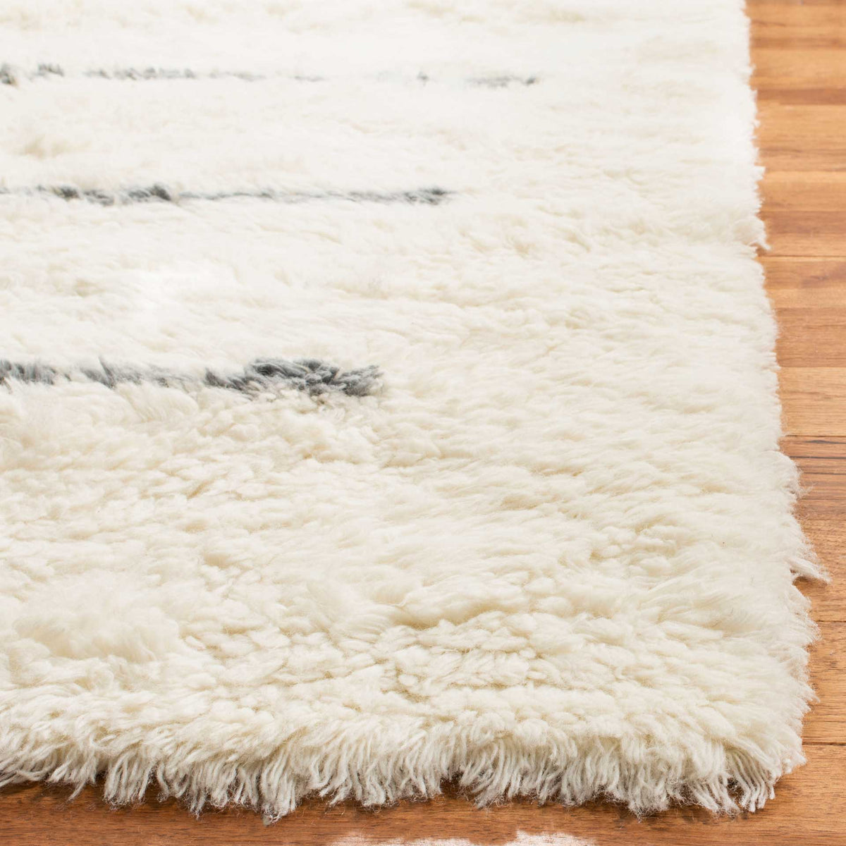 Soft, shaggy ivory wool fibers frame the rug's gray accents and textured corner.