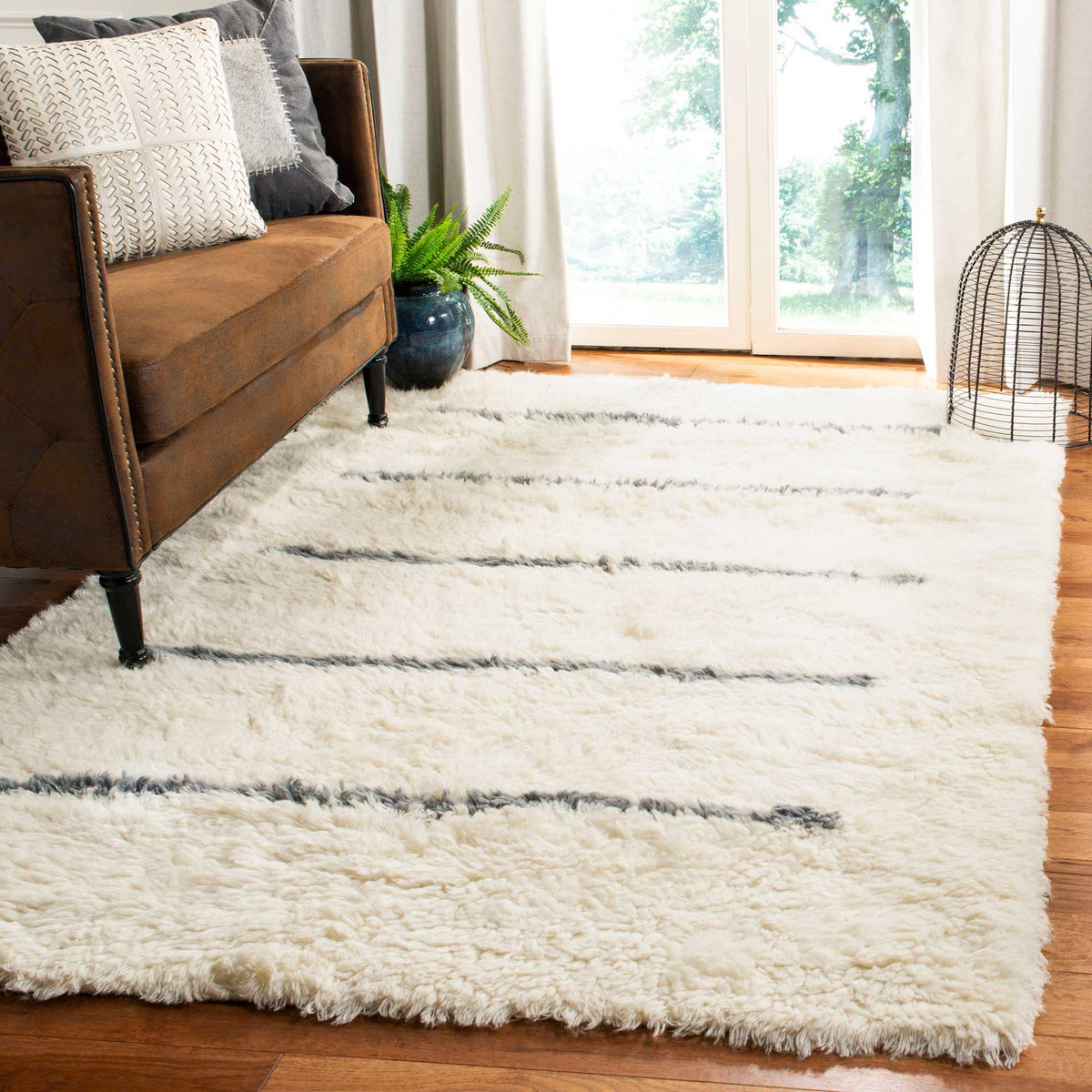 An ivory rug with muted gray stripes lends soft texture beside a brown sofa.