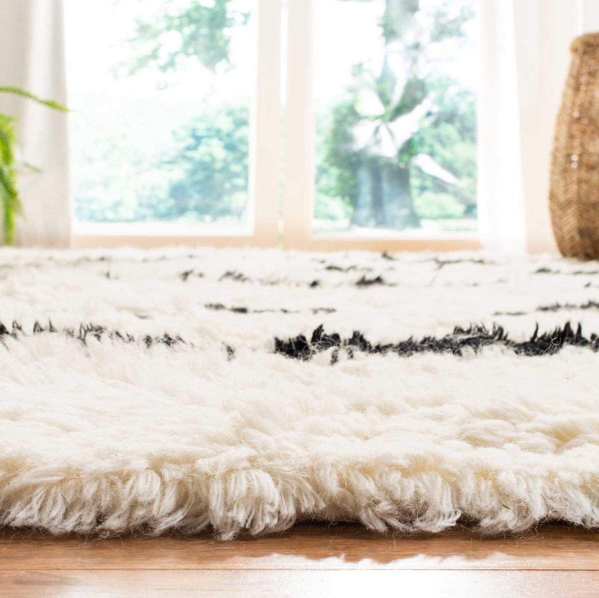 Fluffy ivory fibers cushion the rug's edge beneath scattered black stripe accents.