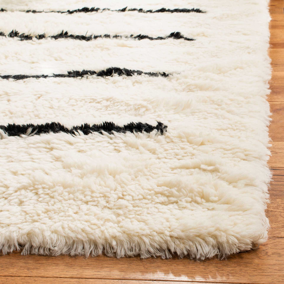 Soft ivory wool pile and inky black stripes meet at the rug's textured corner.