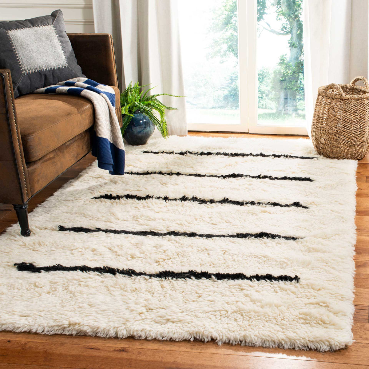 A plush ivory rug with black stripes anchors a cozy space beside a brown sofa.