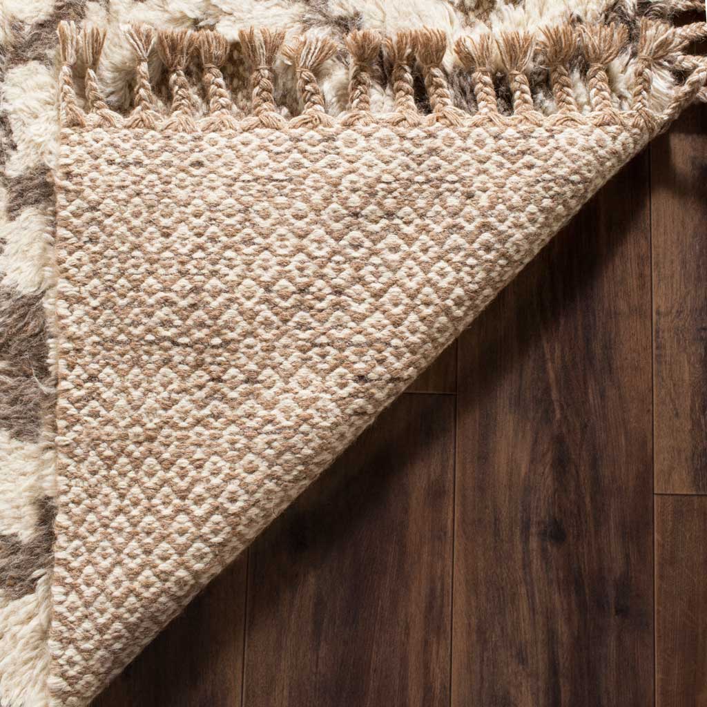 A textured woven underside and knotted fringe highlight the rug's handcrafted finish