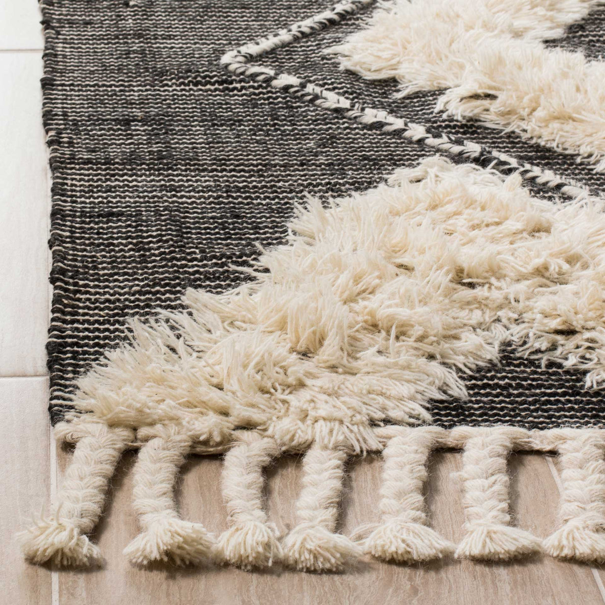 Raised ivory pile contrasts with a flat black weave and thick tasseled fringe